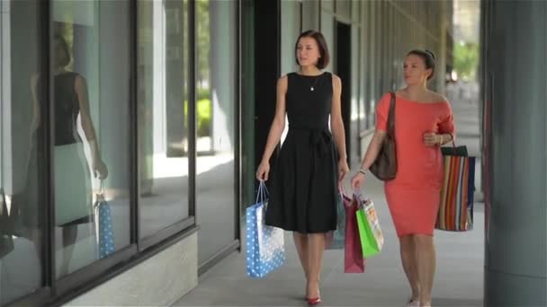 Heureuses jeunes femmes avec des sacs de papier pointant du doigt la vitrine dans la ville, la vente, le consumérisme et le concept de personnes — Video