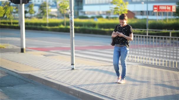 Молодая женщина смс со смартфоном в городском фоне, красивая девушка по телефону — стоковое видео