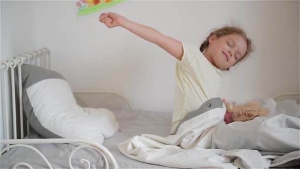 Niña despierta del sueño.Una niña linda disfruta de la mañana soleada. Buenos días en casa. . — Vídeo de stock