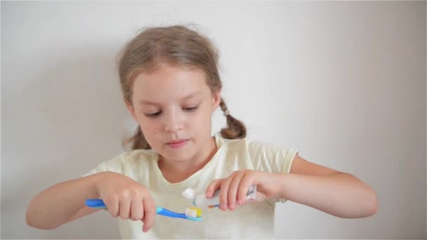 Niña en el baño poniendo una pasta de dientes en el cepillo de dientes — Vídeo de stock