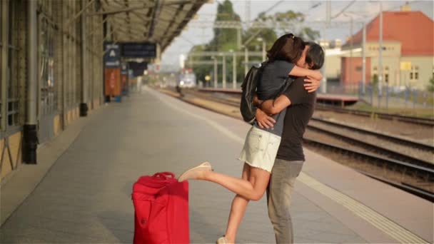 Pareja feliz abrazándose en la plataforma de la estación de tren. Adiós en la estación de tren, jovencita y chico besándose en la plataforma — Vídeo de stock