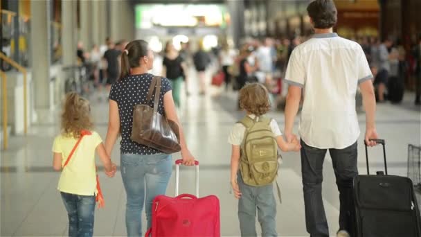 Gelukkig gezin met klein meisje en een jongen gaan op station, vader van de moeder en de kinderen lopen door de luchthaven met koffers — Stockvideo