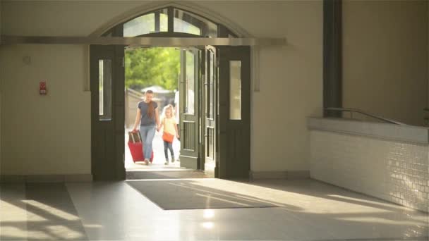 Lächelnde Familie mit Kindern kommt zum Flughafen, junge Mutter, Vater und Kinder auf dem Weg zum Zug am Bahnhof — Stockvideo