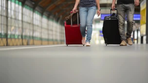 Pies caminando sobre la plataforma de pasajeros con una maleta, joven pareja caminando a lo largo de la plataforma hasta el tren con equipaje — Vídeos de Stock