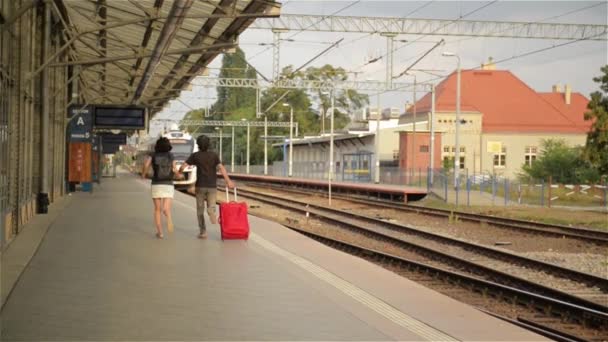 Running couple with a suitcase in a train station — Stock Video