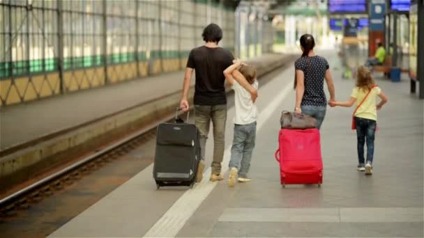 Lycklig familj med liten flicka och pojke går på järnvägsstationen, Mamma, Pappa och barnen gå igenom flygplatsen med resväskor — Stockvideo