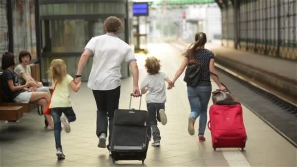 Jovem família de dois cônjuges, filho e filha, correndo para pegar o trem antes de sair da estação ferroviária sem eles, pais e filhos viajando e se atrasar — Vídeo de Stock