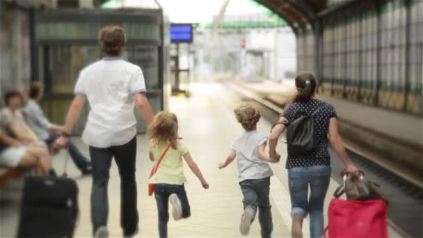 Joven familia de dos cónyuges, hijo e hija, corriendo para coger el tren antes de que salga de la estación de tren sin ellos, padres e hijos viajando y llegar tarde — Vídeos de Stock