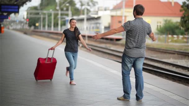 Ungt par glada att träffas igen på järnvägsstationen, flicka körs för att träffa sin pojkvän och kastar en resväska — Stockvideo