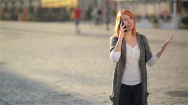 Genç mutlu gülen kadın cep telefonunda söz heyecanlı, kırmızı saçlı kız elini sokak, şehir kentsel arka plan dalgalar..