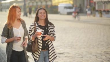 Kız şehirde bir güneşli gün ve içecek kahve üzerinde yürümek