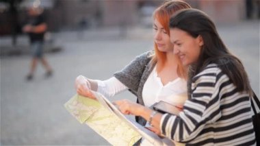 İki çekici kadın turist şehir gülümseyen içinde tatil mutlu seyahat. Kızlar konumlar bulmak için şehir haritası ile. Mutlu tatil.