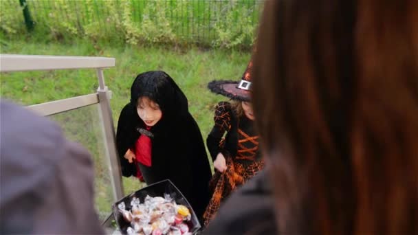 Halloween, los niños quieren dulces de Halloween, los niños que usan disfraces de brujas con sombreros, los niños engañan o tratan . — Vídeos de Stock