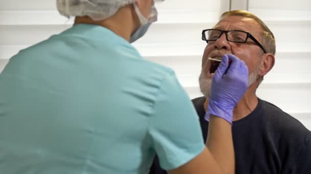 Laboratorietekniker tar äldre patienter smutskastning för att testa för coronavirus. — Stockvideo