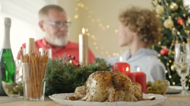 Geroosterde kip op de feestelijke kersttafel en glimlachende familieleden. — Stockvideo