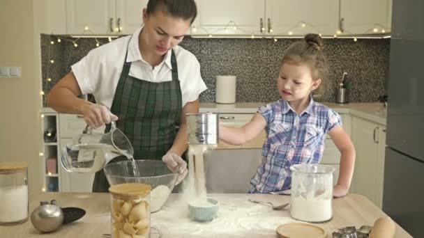 La piccola figlia aiuta sua madre a cucinare un po 'di grana. Divertimento e gratificante tempo in famiglia. — Video Stock