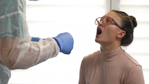 Labortechniker im Schutzanzug nimmt einer Patientin einen Abstrich auf Coronavirus ab. — Stockvideo