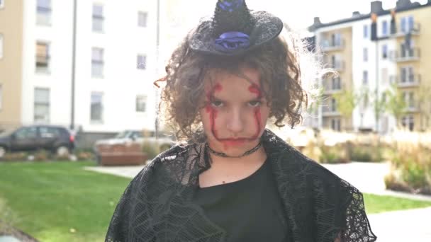 Portrét dospívající dívky oblečené jako čarodějnice s děsivým make-upem na tváři. Halloween. — Stock video