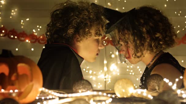 Due adolescenti, una ragazza e un ragazzo in costumi di carnevale nero sullo sfondo di attributi mistici di Halloween. — Video Stock