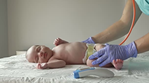 Neonatoloog in latex handschoenen onderzoekt een pasgeboren baby met een stethoscoop. — Stockvideo