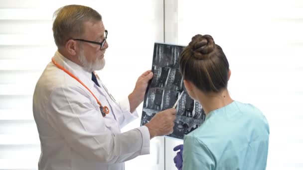 Zwei Ärzte untersuchen Röntgenbilder des Patienten zur Diagnose. — Stockvideo