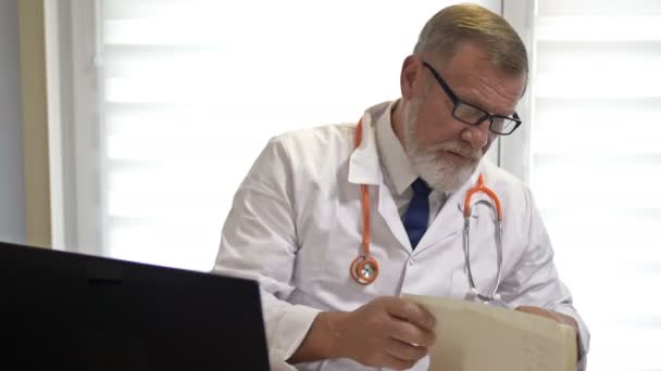 Online-lege. En erfaren lege konsulterer en pasient som bruker laptopen. Covid-19 Epidemi. – stockvideo