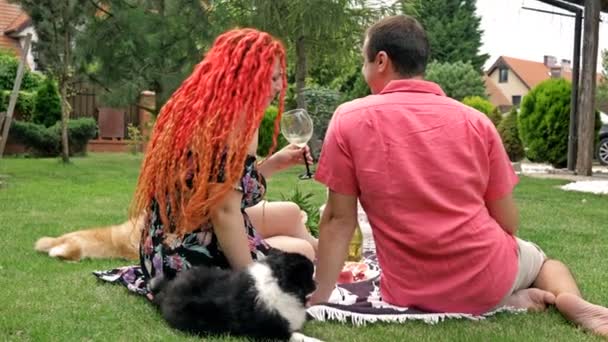 A szerelmesek romantikus piknikeztek a házuk udvarán. A füvön két kis kutya van.. — Stock videók