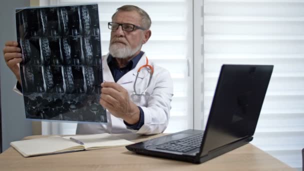 En erfaren traumatolog undersöker en patient röntgen. — Stockvideo