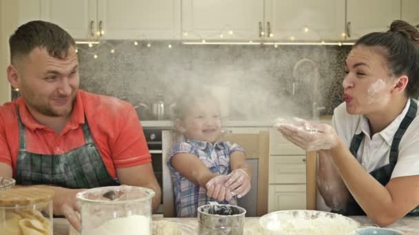 Тато, мама і маленька донька щось готують на кухні. Все перетворюється на веселу гру . — стокове відео