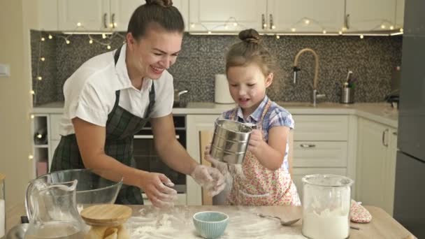 A filhinha ajuda a mãe a cozinhar alguma massa. Tempo de família divertido e gratificante. — Vídeo de Stock