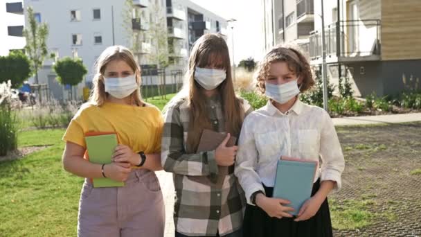 Gruppo di studentesse che indossano maschere mediche per proteggersi dal coronavirus. Ritorno a scuola. — Video Stock