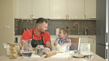 Baba ve kızı 5-6 yaşlarında mutfakta hamur yoğuruyorlar. Baba çocuğuna büyük bir sevgi ve şefkatle davranır..
