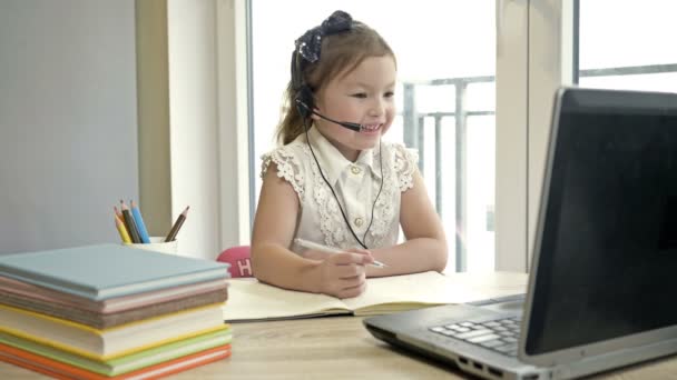 小さな女の子はインターネットを介して教師と通信します。隔離中のオンライントレーニング. — ストック動画