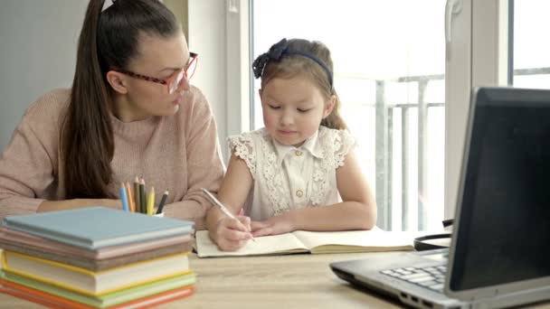 Mom helps a little elementary school student with her homework. Back to school. — Stock Video