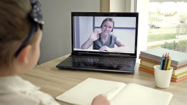 Das kleine Mädchen kommuniziert mit einem Lehrer über das Internet. Online-Schulungen während der Quarantäne. — Stockvideo
