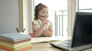 Mesafe öğrenme özellikleri. İnternetten ders. Küçük kız internet üzerinden bir öğretmenle iletişim kuruyor. Karantina sırasında çevrimiçi eğitim.
