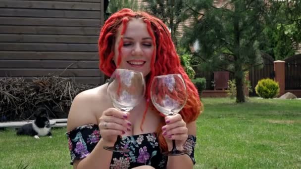 Piknik na trávníku u domu. Mladá veselá žena se dvěma sklenicemi, muž ruka nalévá víno.