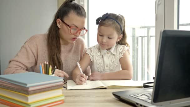 Mladá žena pomáhá své malé dceři s domácím úkolem. Zpátky do školy. — Stock video