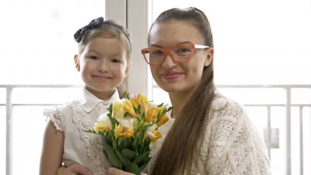 Portrait of a young woman and her little daughter with a bouquet of freesias. Festive mood. — Stock Video