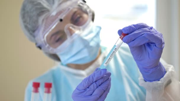 Эксперт работает над вакциной против коронавируса в чистой лаборатории в защитном костюме, перчатках, очках и маске. — стоковое видео