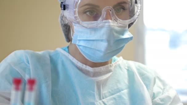 Portret van een vrouwelijke laboratoriumassistent in een beschermend pak. Close-up. — Stockvideo