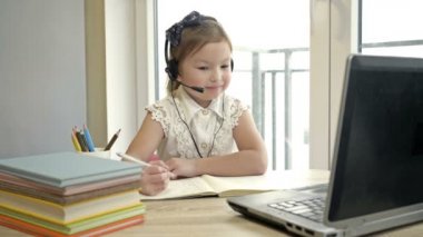 Küçük kız internet üzerinden bir öğretmenle iletişim kuruyor. Karantina sırasında çevrimiçi eğitim.