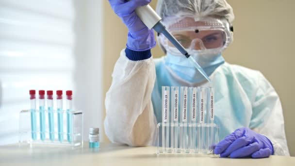Επαγγελματική γυναίκα επιστήμονας σε προστατευτικά γυαλιά και μάσκα κάνοντας πείραμα με αντιδραστήρια στο εργαστήριο. Δημιουργία εμβολίου κατά του coronavirus. — Αρχείο Βίντεο