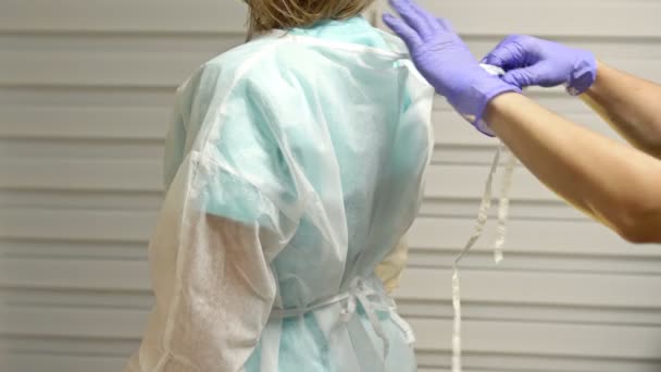 Nurse helps the surgeon to remove the disposable gown after surgery. — Stock Video