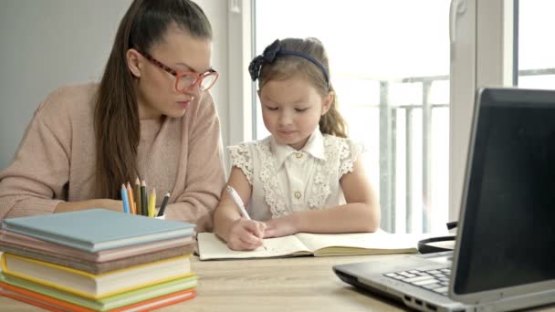 Mama hilft einer kleinen Grundschülerin bei den Hausaufgaben. Zurück zur Schule. — Stockvideo