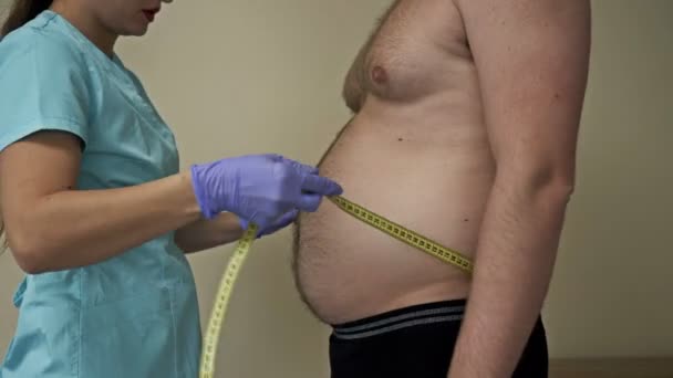 Médico mede a circunferência abdominal de um paciente com sobrepeso. — Vídeo de Stock