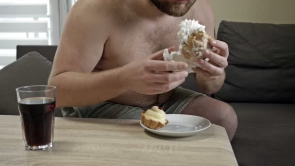 Пухкий чоловік середнього віку жадібно їсть вершкові тістечка. Шкідливі звички їжі . — стокове відео