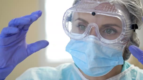 Porträtt av en trött läkare. Kvinnan tar av sig sina glasögon och mask och suckar i lättnad. Närbild. — Stockvideo