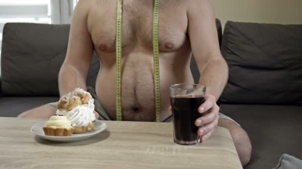 Der übergewichtige Mann ist mit seinem Aussehen beschäftigt. Aber es fällt ihm schwer, auf seine Lieblingsbonbons zu verzichten. Probleme mit ungesunder Ernährung. — Stockvideo