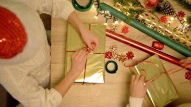 Noel hediyelerini dikkatlice paketleyen iki kadının elleri. Boks günü.